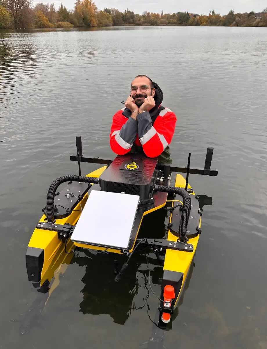 An employer is standing in a lake, leaning satisfied on the insepction boat.