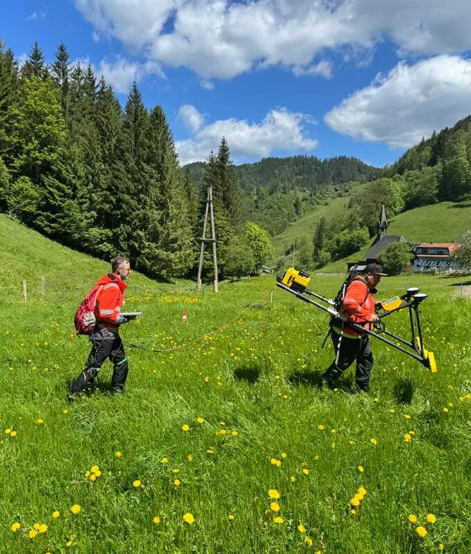 Two inspection operators during pipeline inspection on a green meadow in a hill area.