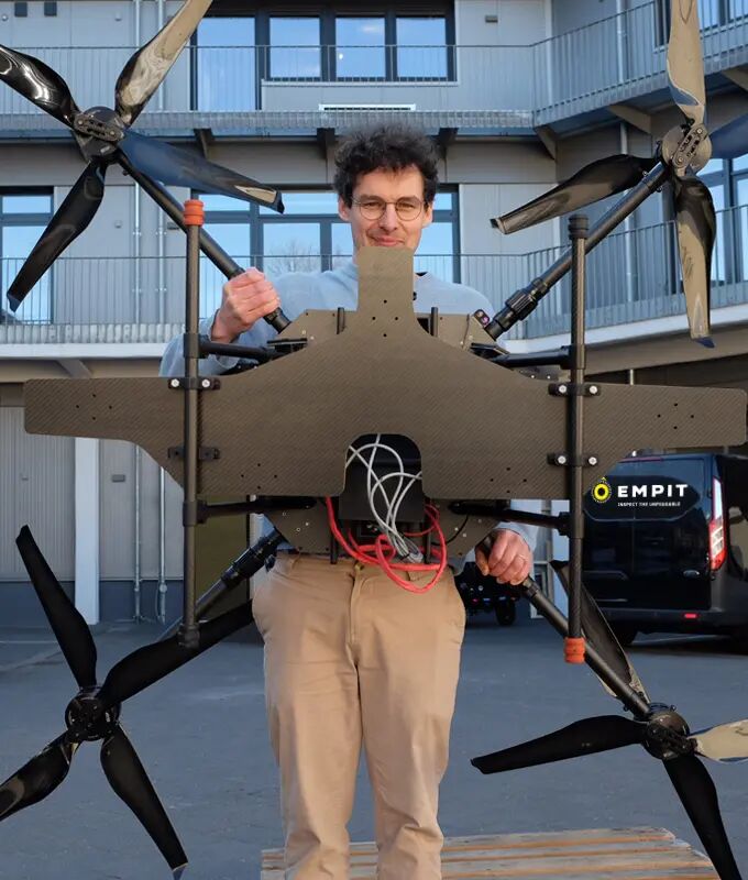 Employee stands outdoors in front of the building complex in Hamburg, holding the inspection drone in the complexe's courtyard.